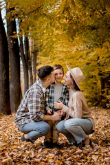 Portrait of happy young family on the background of autumn park. Mom, dad and son are smiling. Family autumn photo shoot