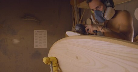 Professional worker with respirator fabricating surfboard by grinder. Workshop scene - Powered by Adobe