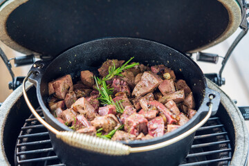 fresh cooking at home on a charcoal grill -  roasted liver, heart and kidneys from a red deer in a dutch oven