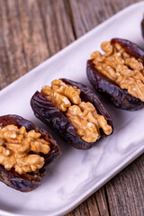 Walnut-stuffed dates on a wood floor. Close-up. Arabian luxury for special occasions such as Ramadan and Eid holidays. local name cevizli hurma