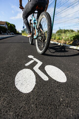 Piste cyclable avec un cycliste le long d'une route, la piste est séparée par un trottoir, le sol...