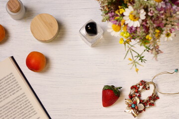 Cosmetic bottles, fruit flowers and book on table, lifestyle staging