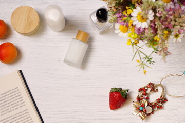 Fototapeta na wymiar Cosmetic bottles, fruit flowers and book on table, lifestyle staging