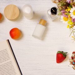 Cosmetic bottles, fruit flowers and book on table, lifestyle staging