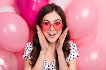 Photo of excited pretty woman wear white dress dark glasses arms cheeks flying balloons isolated...