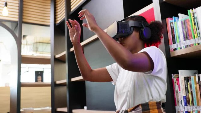 VR headset library. Young teen girl student training and learning with VR virtual teality headset in school library.