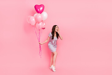Photo of sweet lady dressed dotted dress holding balloons making announcement empty space isolated pink color background
