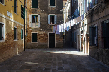 Fototapeta na wymiar Panni stesi ad asciugare fra le case in un campiello veneziano in una giornata di sole