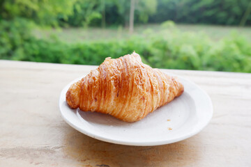Croissant in white container placed on a wooden table.