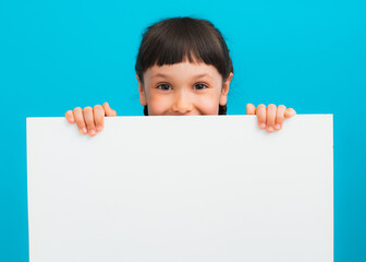 Photo of young happy smiling little girl child kid stand behind white wall isolated on yellow color background