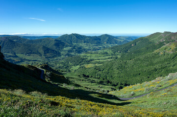 Fototapeta premium Paysage des Monts du Cantal autour du Puy Mary au printemps dans le Parc Régional Naturel des Volcans d'Auvergne en France et vue sur la vallée de La Jordanne