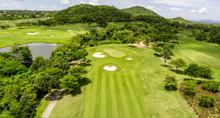 Aerial brid view over of green grass and trees on a golf field, fairway,sand bunker and putting...