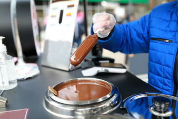 Woman dipping ice cream in chocolate
