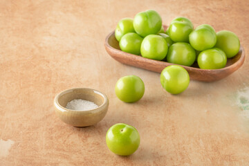 side view ripe green plum fruits served with salt on table