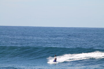 2 australians : a surfer and a jet skier doing Tow-in surfing in Coogee, near Sydney , Australia, in a perfect blue day.