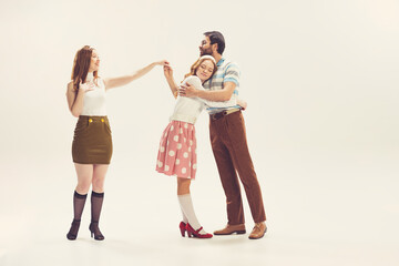 One young man and two girl in vintage retro style outfits psoing isolated on white background. Concept of relationships, family, 1960s american fashion style and art.