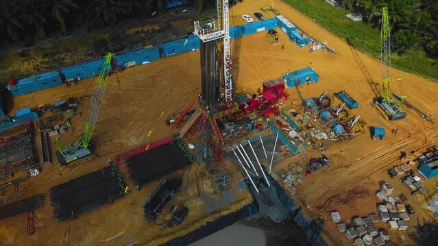 Cinematic Onshore Drilling and Workover Rig structure and Rig equipment for oil exploration and exploitation in the middle of jungle surrounded by palm oil trees during sunset time.