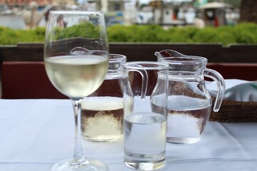 Zwei Karaffen mit Wasser und Wein, ein Weißweinglas, ein Wasserglas. Die Getränke sind eiskalt...