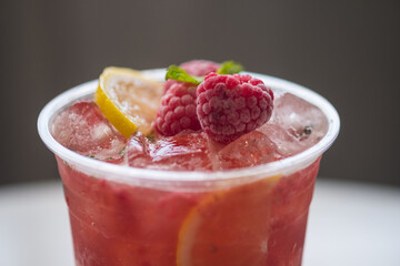 Cold sparkling tea with lemon slice, berry, mint and ice in a glass