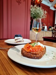 Brioche with poached egg and salmon on the table in front of wine
