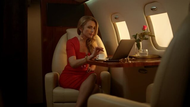 Attractive businesswoman having video call on corporate first class trip alone
