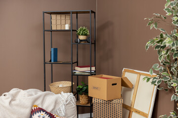 Moving in out, cardboard boxes of packed things stacked on top of each other, a plant in a pot, renting selling an apartment, relocating.