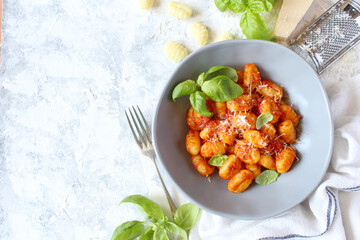 Italian homemade gnocchi with tomato sauce on light background. Top view with copy space.