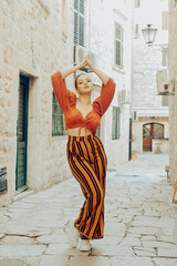 A very beautiful woman poses on the streets of an old city in Europe while traveling. Leisure and vacation in Europe. Beautiful girl with styling.