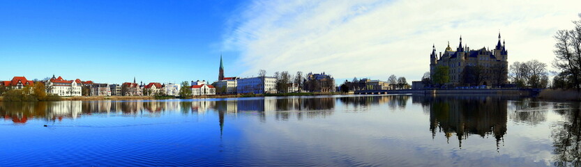 Fototapeta premium weites Panorama vom Schweriner Schloss am schönen Burgsee mit blauem Himmel und weißen Wolken 