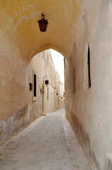 Obraz premium Narrow street with ancient stone houses and antique lantern on the wall in Mdina,also called Silent City. Malta, Europe. 