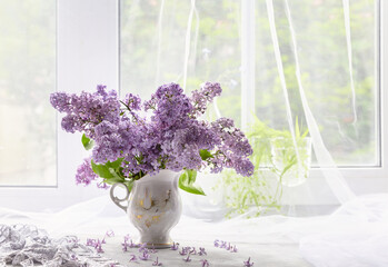 A bouquet of lilacs in a vase on a white windowsill. Still life with lilacs