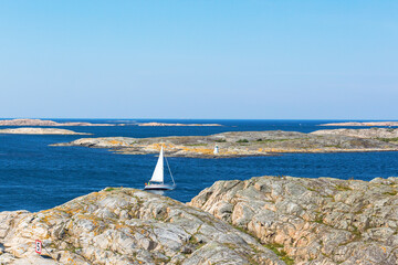 View of rocky coastline with sailboat at sea
