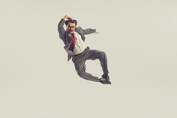 Emotional jumping man, businessman wearing grey striped suit in 50s, 60s fashion style flying...