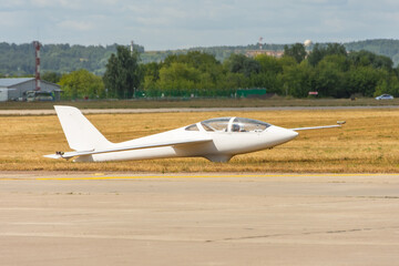 Ultralight glider plane stands on the grass, landing on earth aerodrome.