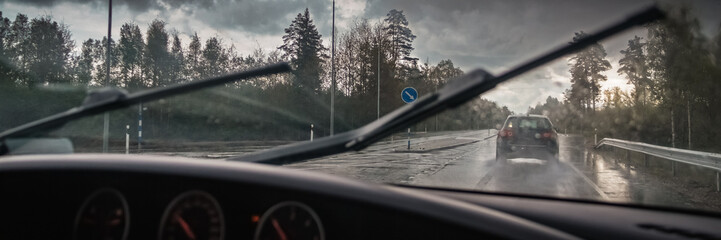 View of the road wet from the rain through the windshield of the car.