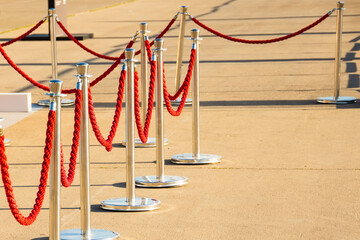 Silver plated barrier posts with red velvet ropes with red event carpet.