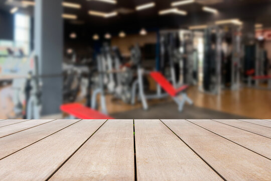 Empty old wooden table in front of blurred background of the gym equipment. Can be used for display or montage for show your products.
