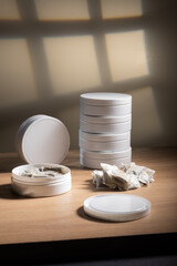Studio shot of white swedish smokeless tobacco cans and portion snus pouches on a wooden table.