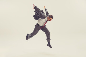 Jumping man, businessman wearing grey striped suit in 50s, 60s fashion style hurring isolated on white background. Retro vintage style, business, ad, emotions