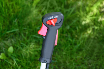 Gas handle for a gas trimmer, lawn mowers on a green background close-up. Knob with trimmer controls