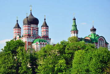 Fototapeta na wymiar Domes or cupolas with Eastern Orthodox crosses of monastery churches seen through trees on sky
