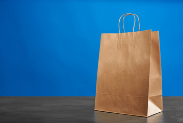 A brown paper bag with handles on a blue background. ECO bag. Craft paper bag. Recycled paper....