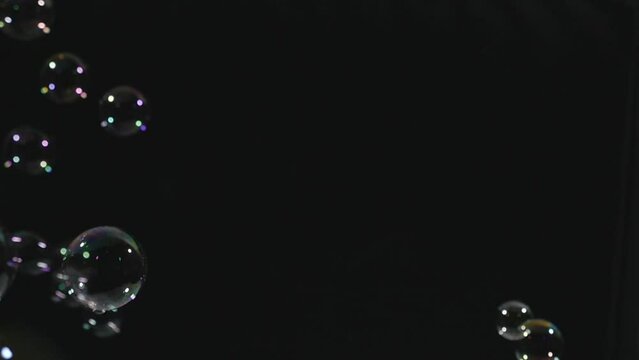 Soap bubbles flying through black background. Abstract.