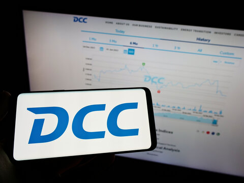 Stuttgart, Germany - 06-04-2022: Person holding mobile phone with logo of Irish sales and marketing company DCC plc on screen in front of business web page. Focus on phone display.