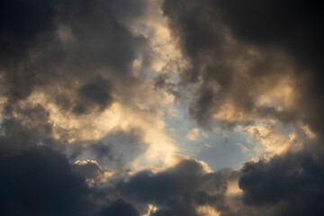 Fototapeta na wymiar Dark gray clouds fly across the sky. Puffy fluffy grey clouds at spring day during sunset