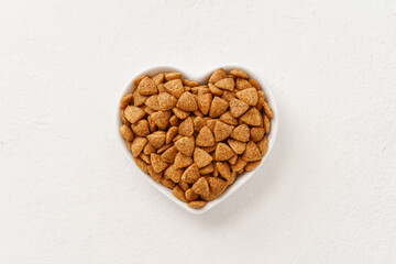 Cat food in a heart-shaped bowl close-up in the center of the frame top view