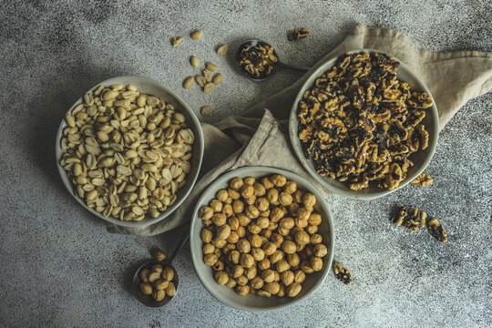 Overhead view of three bowls of hazelnuts, walnuts and peanuts
