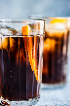 Close-Up of two cola drinks with ice cubes and a slice of orange
