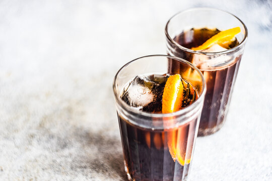Close-up of two cola drinks with ice cubes and slices of fresh orange
