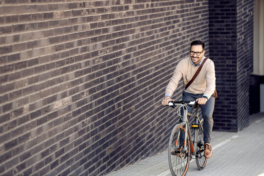 A casual businessman riding a bicycle on the street uphill.